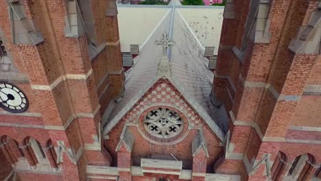 A-beautiful-old-Church-top-close-up-aerial-view,-A-pigeon-flew-over-the-Church-Cross,-A-clock-on-the-wall-of-the-Church