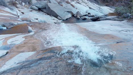 Aerial-close-up-of-a-waterfall-flowing-down-a-granite-rock-face