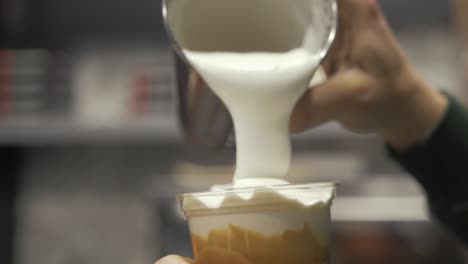 Barista-pouring-frothy-milk-over-freddo-cappuccino-in-slow-motion
