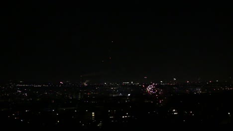 Fireworks-shooting-up-in-foreground-with-more-fireworks-going-off-over-city-in-background