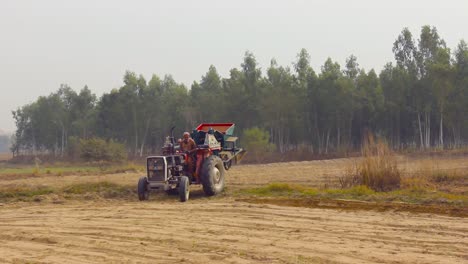 A-farmer-operates-his-tractor-in-the-field-near-a-Eucalyptus-forest