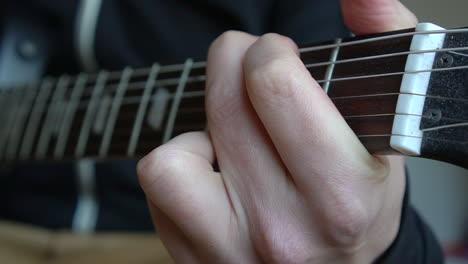 Man-Practising-a-vintage-black-electric-guitar,-rehearsing-chords,-solos-and-octaves-in-a-natural-light-environment.