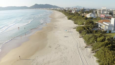Drohne-Fliegt-über-Einen-Strand-Mit-Hereinrollenden-Wellen---Küstenlandschaft-Mit-Bergen-Im-Hintergrund-Eines-Tropischen-Paradiesstrandes-Mit-Weißem-Sand-Und-Blauem-Wasser-Des-Brasilianischen-Ozeans