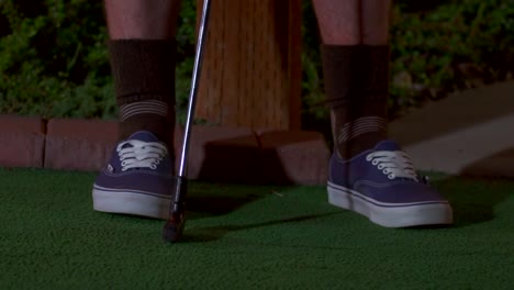 A-close-up-of-a-purple-mini-golf-ball-getting-hit-with-a-club