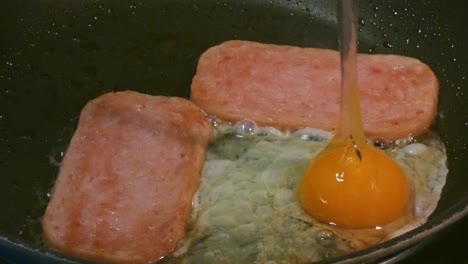 Spam-in-a-frying-pan-and-adding-a-egg-to-the-fry-up-for-a-unhealthy-high-cholesterol-breakfast