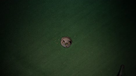 A-wide-shot-of-a-yellow-mini-golf-ball-going-in-the-hole