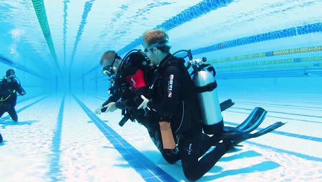 Two-scuba-instructors-demonstrating-safety-procedures-to-a-group-of-students