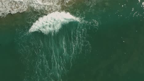 Afternoon-camera-down-drone-view-and-following-one-small-wave-in-Redondo-Beach,-California