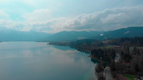 Slow-aerial-pan,-showing-the-lake-Tegernsee-with-the-Wallberg-in-the-background-on-a-spring-day