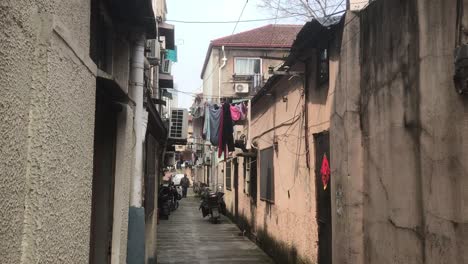 hand-held-shot-of-an-urban-genuine-musty-backyard-area-in-French-Concession,-Shanghai-on-a-cold-wet-spring-day