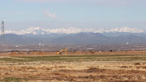Construction-equipment-working-on-a-housing-development-near-Denver,-Colorado-with-the-Rocky-Mountain-front-range-in-the-background