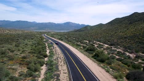 Aerial-slow-ascent-from-road-level-where-traffic-is-heading-back-to-Scottsdale-from-Bartlett-Lake,-Tonto-National-Forest,-Sonoran-Desert,-Arizona,-Concept:-transportation,-travel,-springtime