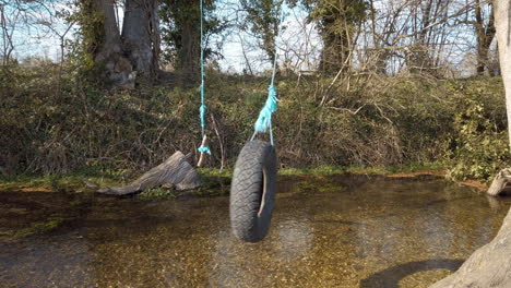 A-tyre-and-rope-swing-hanging-over-a-shallow-stream-in-the-countryside