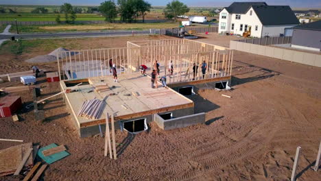 A-drone-shot-slowly-pushing-in-on-construction-framers-putting-up-walls-on-a-new-home-in-the-process-of-being-built