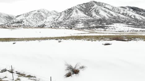 Snow-covered-field-at-the-base-of-mountains-in-winter