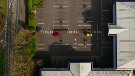 Topdown-aerial-moving-slowly-over-a-car-park-in-a-small-retail-park