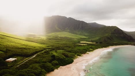 Wunderschöne-4K-Drohne,-Die-über-Die-Küste-Von-Makua-Beach-Auf-Der-Westseite-Von-Oahu-Schwenkt,-Wobei-Morgensonnenstrahlen-über-Die-Grünen-Berge-Schwappen