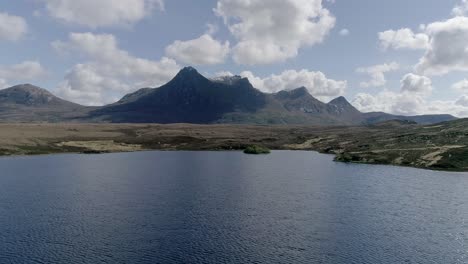 Aerial-travelling-low-above-a-loch-with-the-prominent-mountain-range-of-Ben-Loyal-in-the-background
