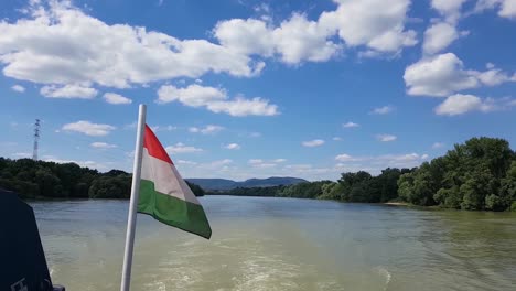 Navegación-A-Cámara-Lenta-Con-Un-Barco-En-Un-Río-Con-Nubes-Esponjosas-En-Un-Día-Soleado-De-Verano-Bandera-Húngara