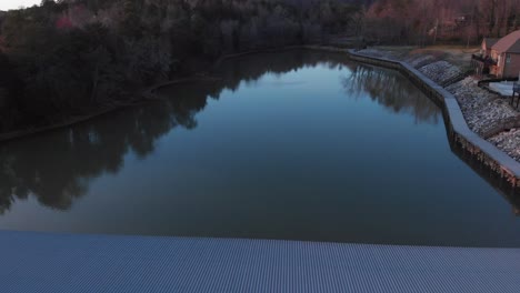 Drone-footage-flying-backwards-over-boat-docks-with-nice-houses-to-the-right-and-calm-water-at-sunset