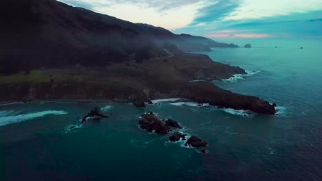 Fast-orbit-around-huge-ocean-cliff-peninsula-eroded-by-crashing-waves-at-dusk-at-Sand-Dollar-Beach-in-Big-Sur-California