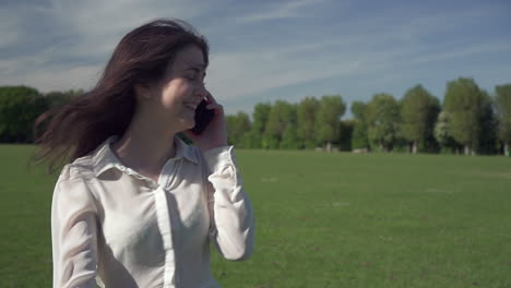 Steadicam-shot-of-a-young-beautiful-Italian-girl-in-a-great-mood-on-while-walking-in-the-park-and-talking-on-the-phone