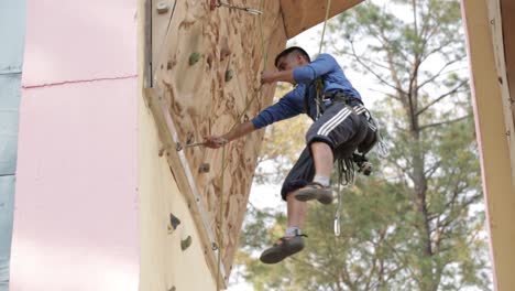 Fitness,-extreme-sport,-outdoor-bouldering,-people-and-healthy-lifestyle-concept---young-man-exercising-at-indoor-climbing-gym-wall