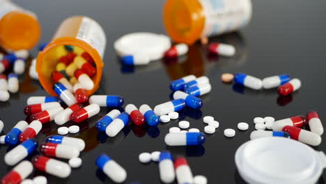 Many-prescription-pills,-drugs,-antibiotics-and-antidepressants-spilling-in-slow-motion-from-an-orange-pharmacy-medicine-bottle