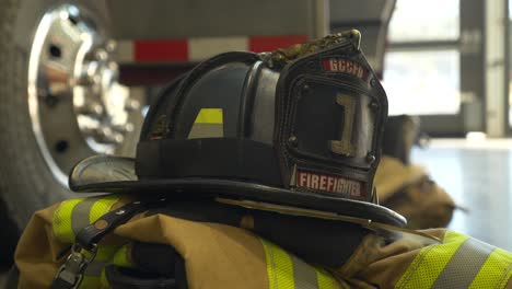 Firefighter-helmet-on-top-of-firefighting-gear-with-fire-truck-in-background