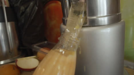 Close-up-of-Mans-hand-filling-bottle-with-freshly-squeezed-orange-juice