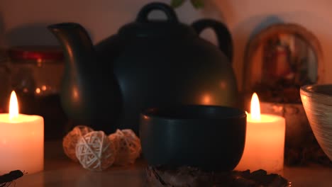 Relaxing-background-detail-shot-of-an-herbal-tea-shop,-with-candles-with-flickering-flames,-a-tea-pot-and-a-cup-with-steam-coming-out