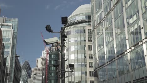 Close-up-shot-of-CCTV-cameras-in-London-with-sunlight-reflections-on-the-windows-of-tall-buildings