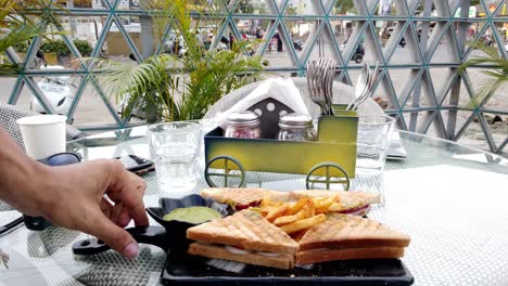 A-Server-or-Waiter-Serves-a-Sandwich-with-Fries-at-a-Cafe-Table-to-Guests