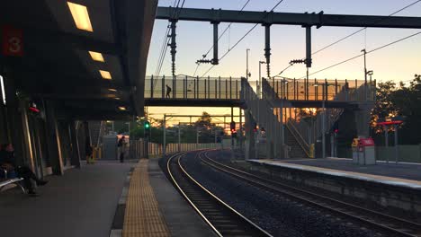 Blick-Auf-Die-Gleise,-Wenn-Die-Sonne-Aufgeht-Und-Pendler-Am-Frühen-Morgen-Die-Brücke-Zu-Einem-S-Bahnhof-überqueren