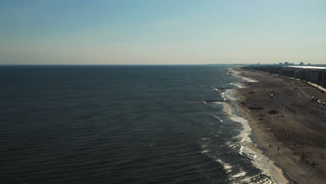 aerial-pull-away-over-the-ocean-with-the-shoreline-on-the-right-side-of-the-shot