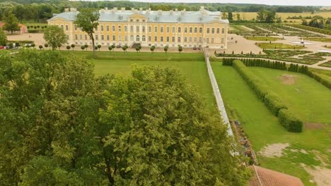 Aerial-shot-flying-over-a-trees-revealing-the-Rundale-Palace,-in-Latvia
