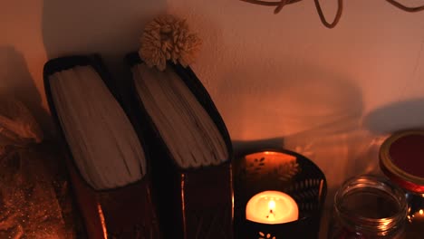 Relaxing-background-detail-shot-of-candles-with-flickering-flames,-some-herbs,-ancient-books,-jars-and-some-dust-flying-around
