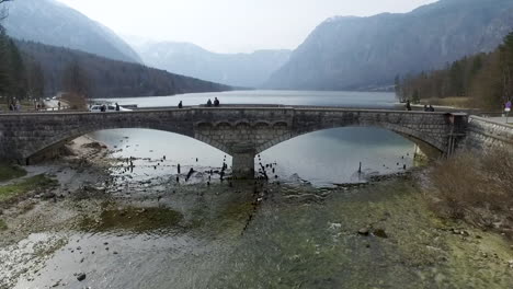 Flying-backwards-over-the-bridge-from-the-Bohinj-lake,-Slovenia