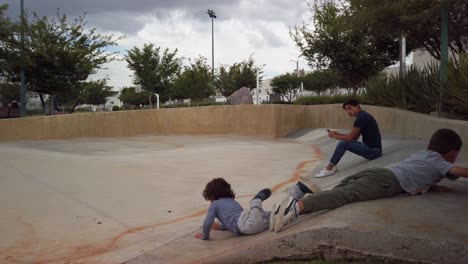 Boy-sliding-downwards-on-a-concrete-ramp-at-Saki-Park-on-a-really-cloudy-day