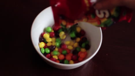 Close-Up-Pouring-Skittles-Candy-Into-White-Bowl