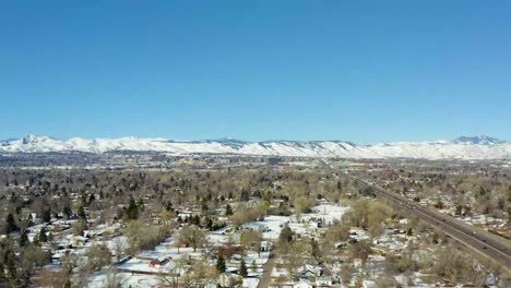 Eine-Luftaufnahme-Der-Straßen-In-Einer-Stadt-Mit-Blick-Auf-Einen-Schneebedeckten-Berg-In-Denver-Im-Winter