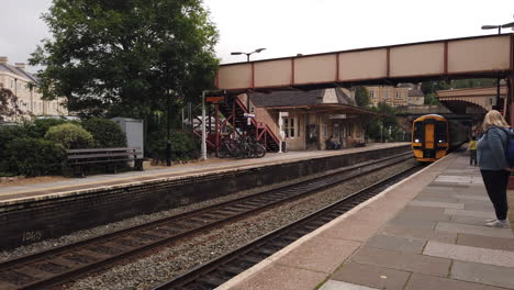 Tren-Gwr-Acercándose-A-La-Estación-Bradford-On-Avon-En-Wiltshire-En-Un-Día-De-Verano-Nublado-Con-Pasajeros-Caminando-Por-La-Plataforma