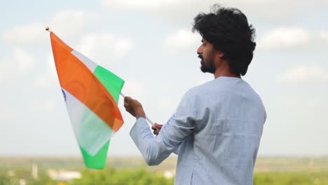 The-young-man-with-traditional-Indian-dress-holding-Indian-Flag-on-a-sunny-day