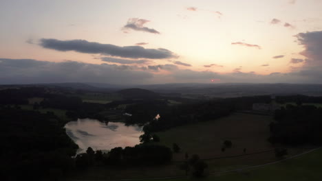 Falling-Aerial-Shot-of-a-Country-Estate-and-Lake-during-Sunset