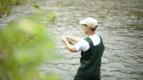 Slow-Motion-Shot-of-a-Caucasian-male-fisherman-casting-his-hook-while-Fly-Fishing