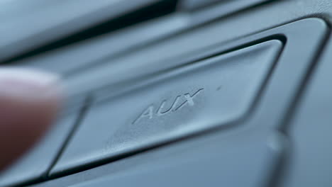 Close-up-of-a-finger-pushing-the-aux-button-on-a-car-dash