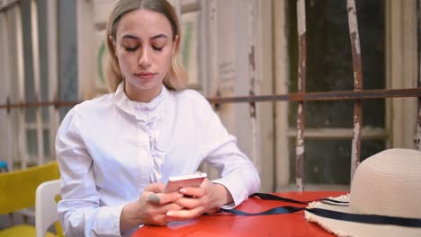 Slow-Motion:Attractive-young-beautiful-girl-uses-smart-phone-while-sitting-at-a-cafe-outside