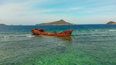 Ein-Schiffswrack-Auf-Einem-Riff-Mit-Epischen-Blicken-Auf-Inseln-Im-Hintergrund-In-Der-Karibik
