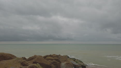 Brighton-beach-on-a-cloudy-day-with-seagulls-flying-past-camera,-shot-panning-along-beach
