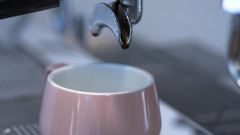 Changing-coffee-cup-and-portafilter-on-coffee-machine-in-light-cafe,-closeup